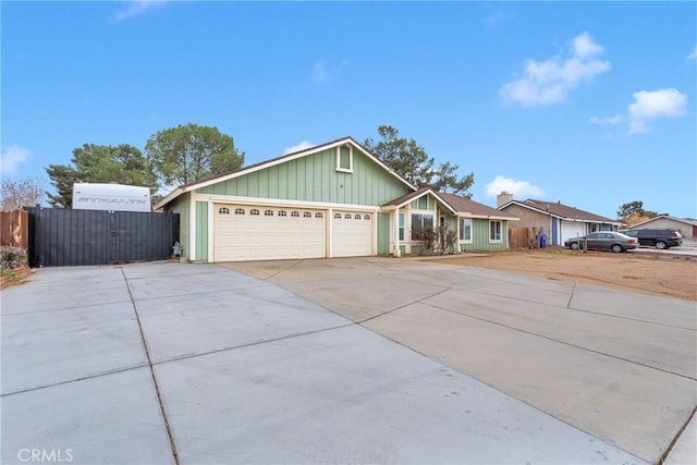 ranch-style home featuring driveway, board and batten siding, an attached garage, and fence