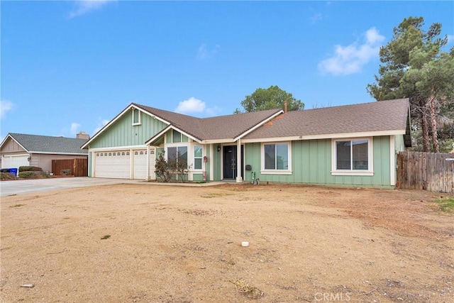 ranch-style home with driveway, an attached garage, fence, and board and batten siding