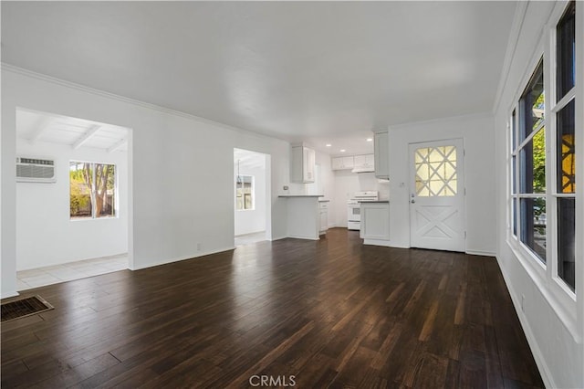 unfurnished living room with dark hardwood / wood-style flooring, a wall unit AC, and beamed ceiling