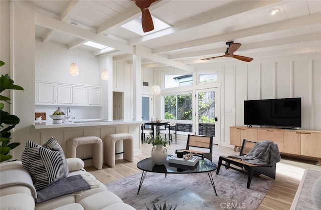 living room with beamed ceiling, sink, ceiling fan, and light hardwood / wood-style floors