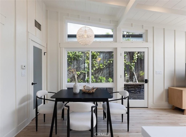 interior space with lofted ceiling with beams, a healthy amount of sunlight, light wood-type flooring, and a notable chandelier