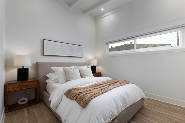 bedroom featuring beam ceiling and light hardwood / wood-style flooring