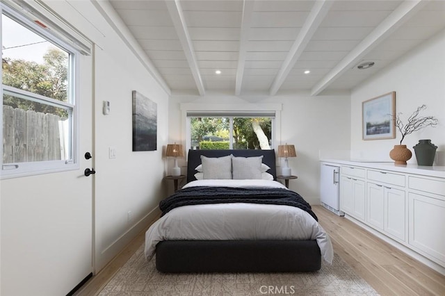 bedroom featuring beam ceiling, multiple windows, and light hardwood / wood-style flooring