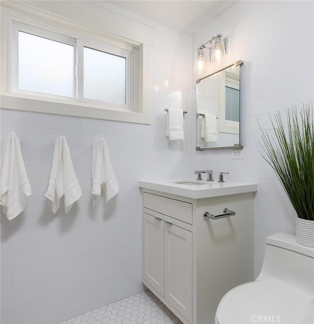 bathroom with tile walls, vanity, and toilet