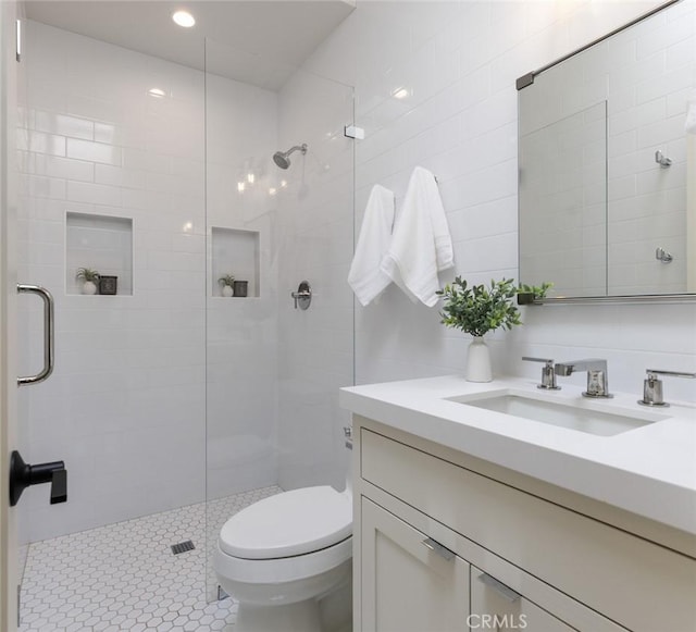 bathroom with vanity, toilet, an enclosed shower, and tile walls