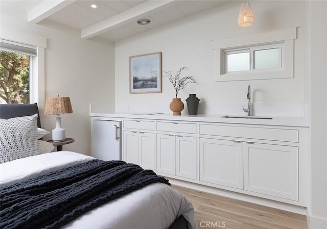 bedroom with built in refrigerator, sink, beam ceiling, and light wood-type flooring