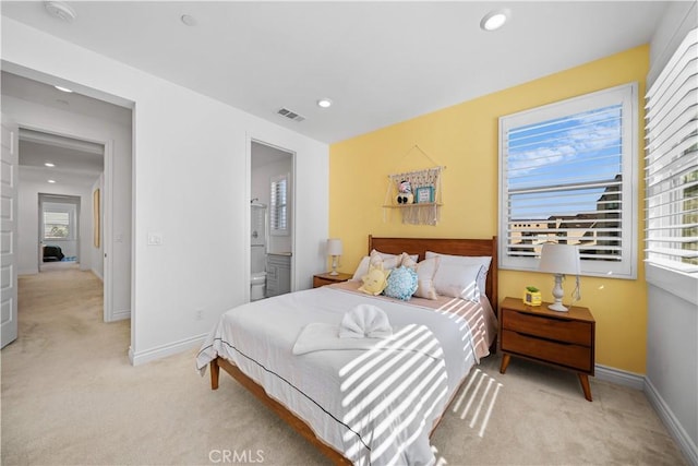 bedroom featuring multiple windows, ensuite bathroom, and light carpet