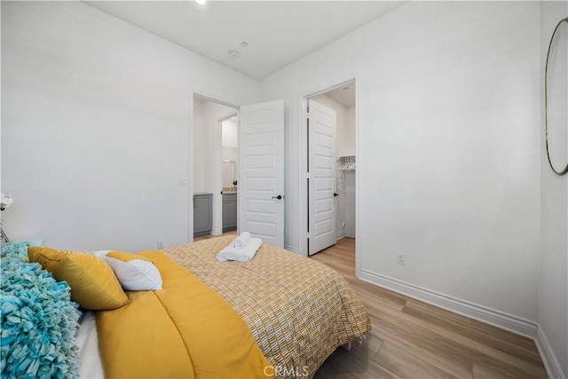 bedroom featuring a walk in closet and light hardwood / wood-style flooring