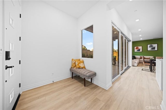 hall with baseboards, light wood finished floors, and recessed lighting