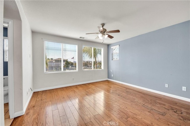 empty room with visible vents, ceiling fan, light wood-style flooring, and baseboards