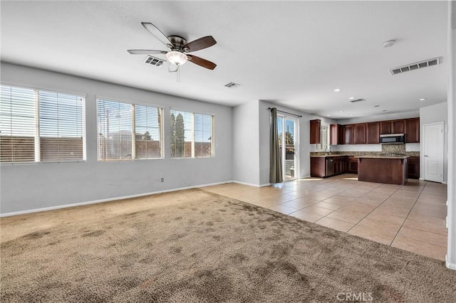 unfurnished living room with visible vents, light carpet, and light tile patterned floors