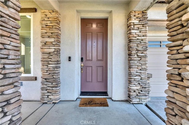 entrance to property featuring stone siding and an attached garage