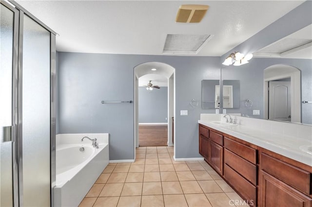 full bath featuring double vanity, a bath, ceiling fan, tile patterned floors, and a sink