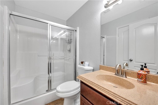 full bath with a stall shower, visible vents, vanity, and toilet