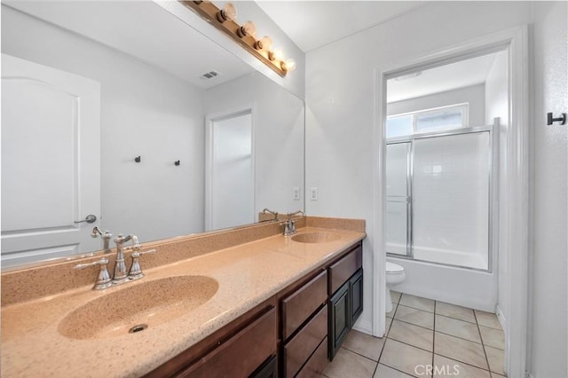 bathroom with double vanity, tile patterned flooring, bath / shower combo with glass door, and a sink