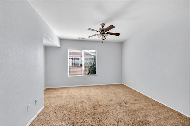 carpeted empty room featuring baseboards, visible vents, and a ceiling fan