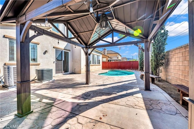 view of patio / terrace with a fenced backyard, central AC, a fenced in pool, and a gazebo