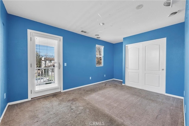 unfurnished bedroom with a closet, carpet flooring, visible vents, and baseboards