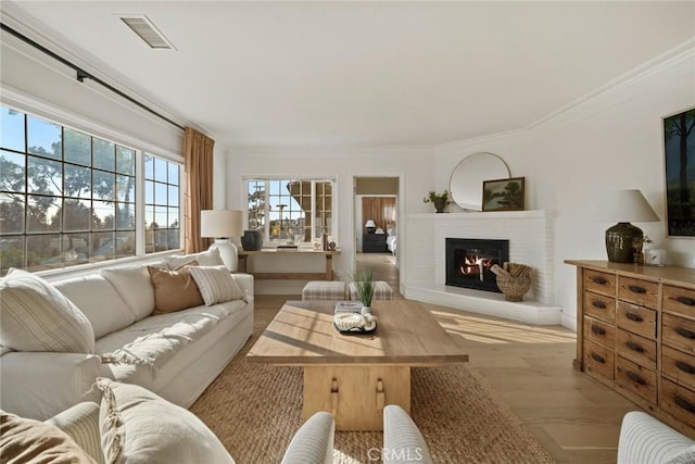 living room with crown molding, visible vents, a fireplace, and wood finished floors