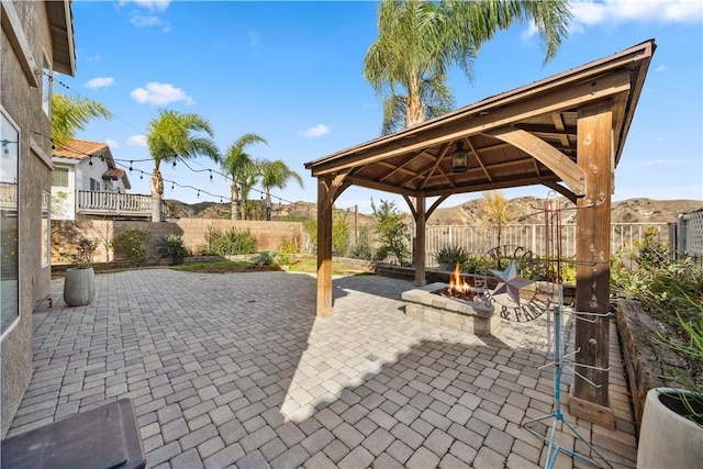 view of patio / terrace with an outdoor fire pit, a fenced backyard, and a gazebo