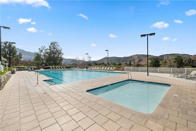 pool with a patio area, fence, and a mountain view