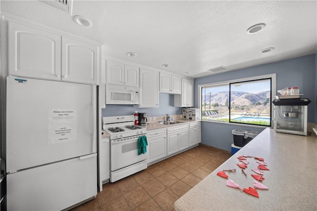 kitchen featuring white appliances, white cabinets, light countertops, a sink, and light tile patterned flooring