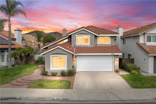 mediterranean / spanish-style house featuring a tiled roof, concrete driveway, a mountain view, and stucco siding