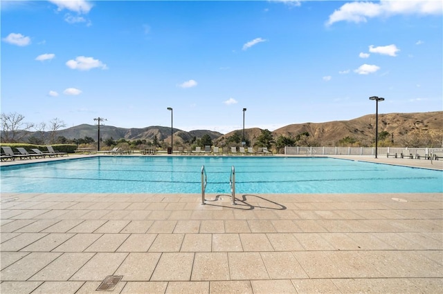 view of swimming pool with fence and a mountain view