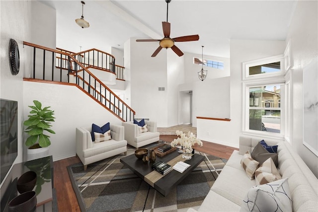 living area featuring dark wood-style floors, visible vents, ceiling fan, high vaulted ceiling, and stairs