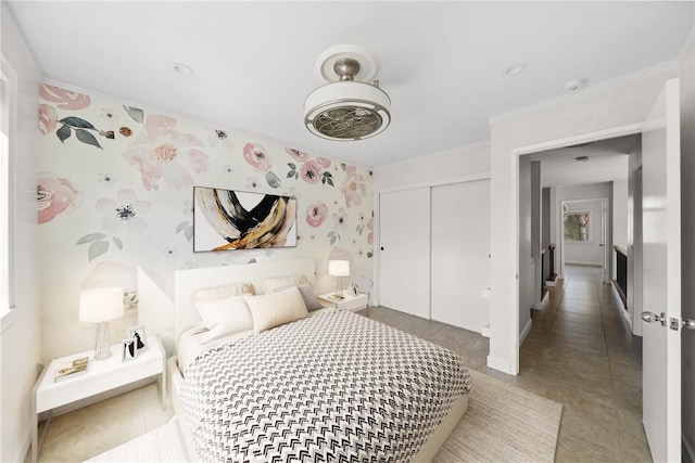 bedroom with wallpapered walls, ornamental molding, and a closet