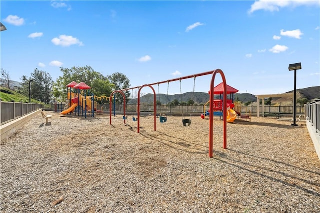 community play area featuring a mountain view and fence