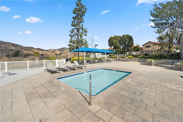 community pool with a patio area, a mountain view, and fence