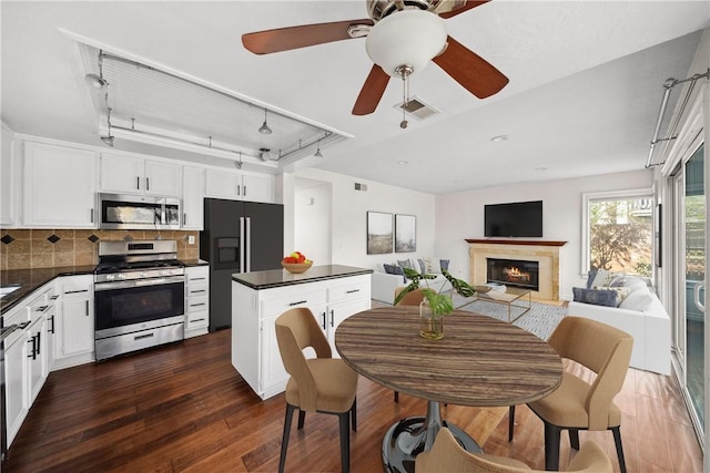 kitchen featuring open floor plan, appliances with stainless steel finishes, dark countertops, and visible vents