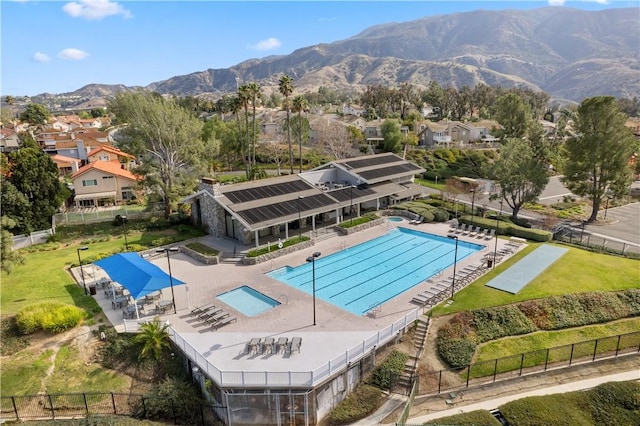 pool with a residential view, a patio area, fence, and a mountain view