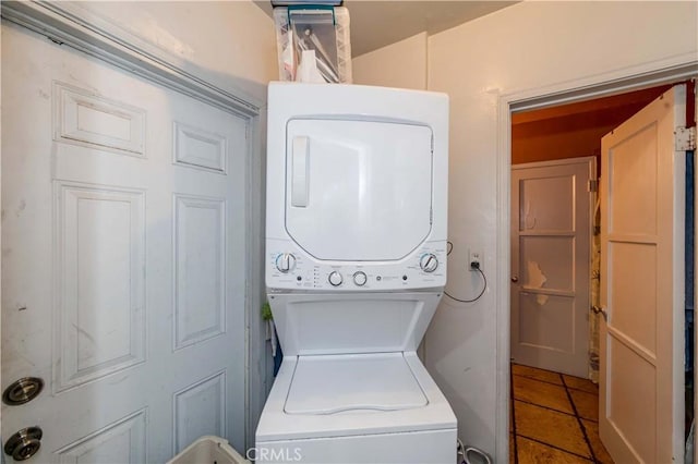 clothes washing area with tile patterned flooring and stacked washer and clothes dryer