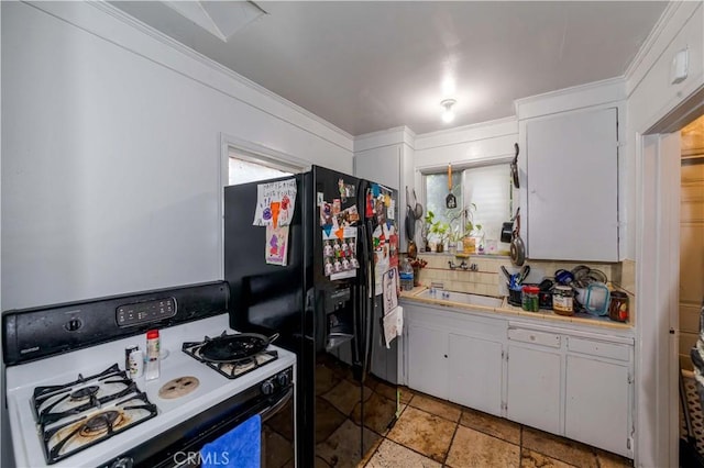 kitchen with sink, gas range, white cabinetry, black refrigerator with ice dispenser, and backsplash