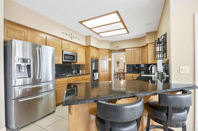 kitchen with a peninsula, appliances with stainless steel finishes, and a breakfast bar