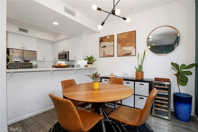 dining area with an inviting chandelier, wine cooler, and dark hardwood / wood-style flooring