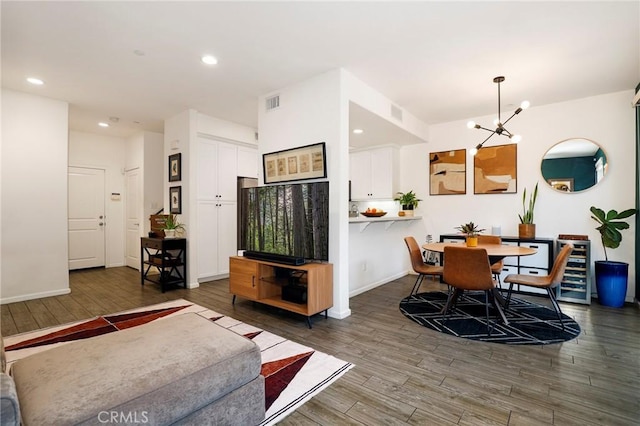 living room with dark wood-type flooring, a notable chandelier, and beverage cooler