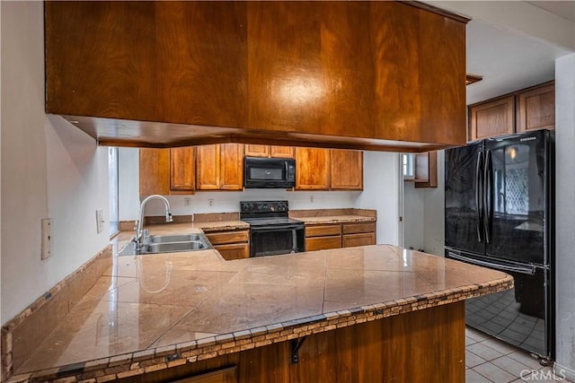 kitchen featuring sink, kitchen peninsula, tile counters, and black appliances