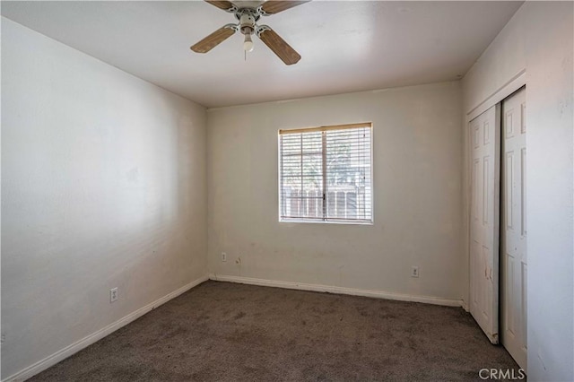 unfurnished bedroom featuring ceiling fan, dark carpet, and a closet