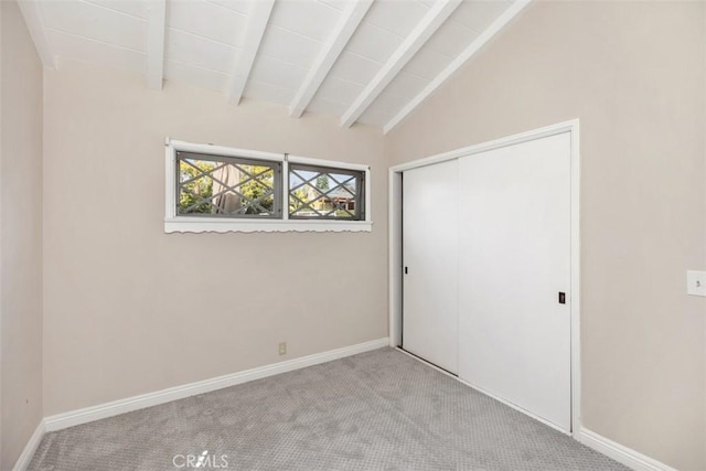 unfurnished bedroom featuring light colored carpet, lofted ceiling with beams, and a closet