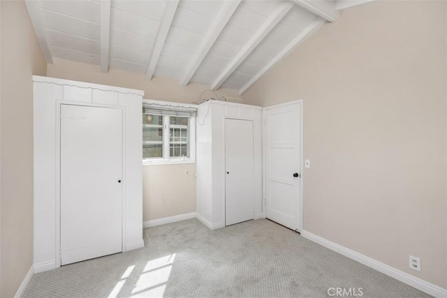 unfurnished bedroom featuring light carpet and lofted ceiling with beams