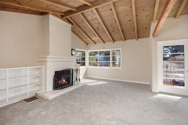 unfurnished living room featuring beam ceiling, carpet, a brick fireplace, and wooden ceiling