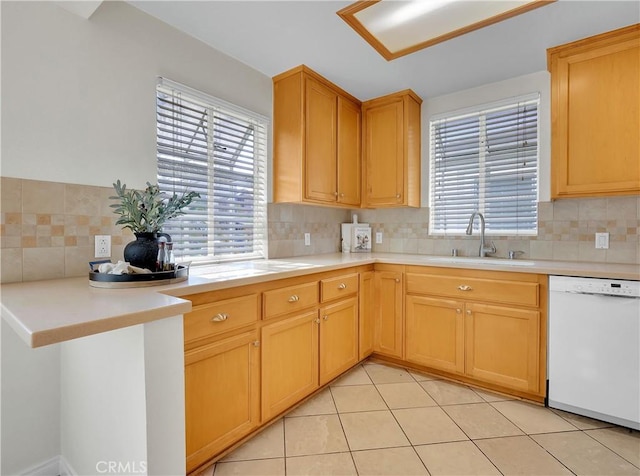 kitchen with light tile patterned floors, white dishwasher, a sink, light countertops, and decorative backsplash