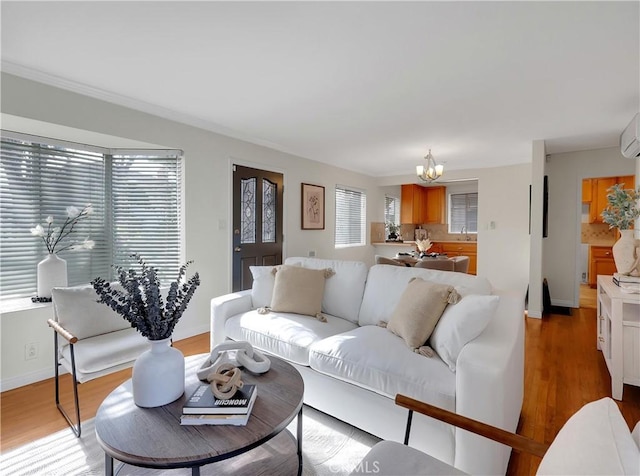 living area featuring baseboards, a chandelier, wood finished floors, and a wall unit AC