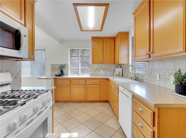 kitchen with tasteful backsplash, light tile patterned floors, a sink, light countertops, and white appliances