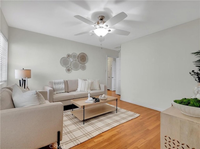 living area featuring ceiling fan, light wood-type flooring, and baseboards