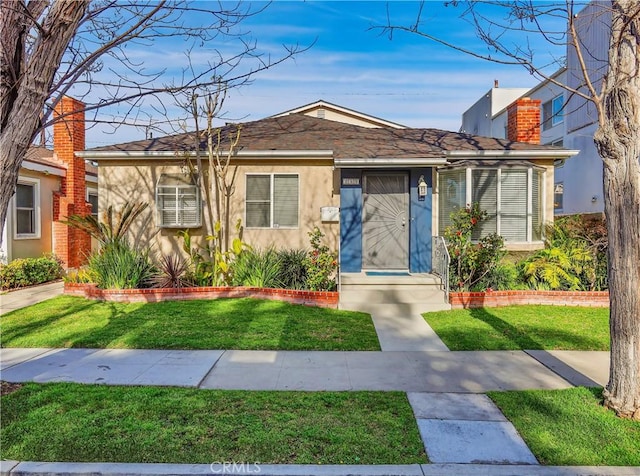 bungalow-style home with a chimney, a front lawn, and stucco siding