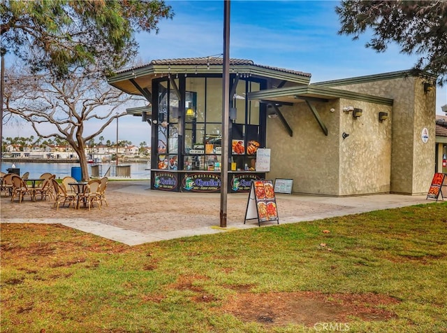 exterior space featuring a yard, a water view, and stucco siding
